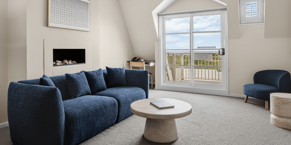 Lounge room featuring lounge suite , occasional chairs, and coffee table with window and balcony in background