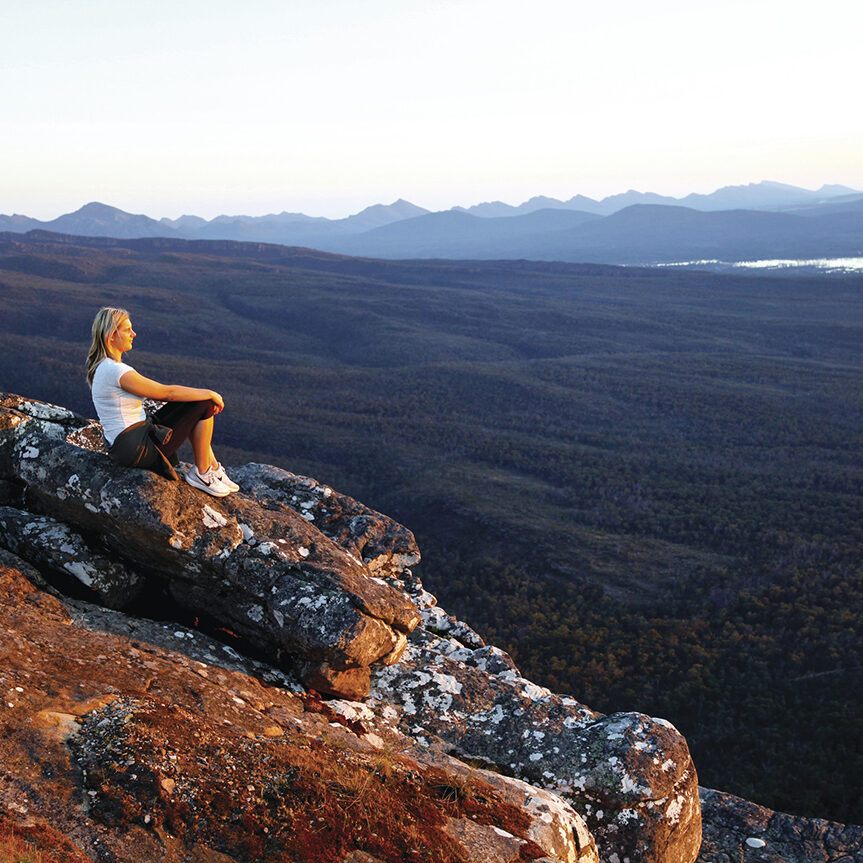Hiker sitting atop mountain overlooking Grampians National Park